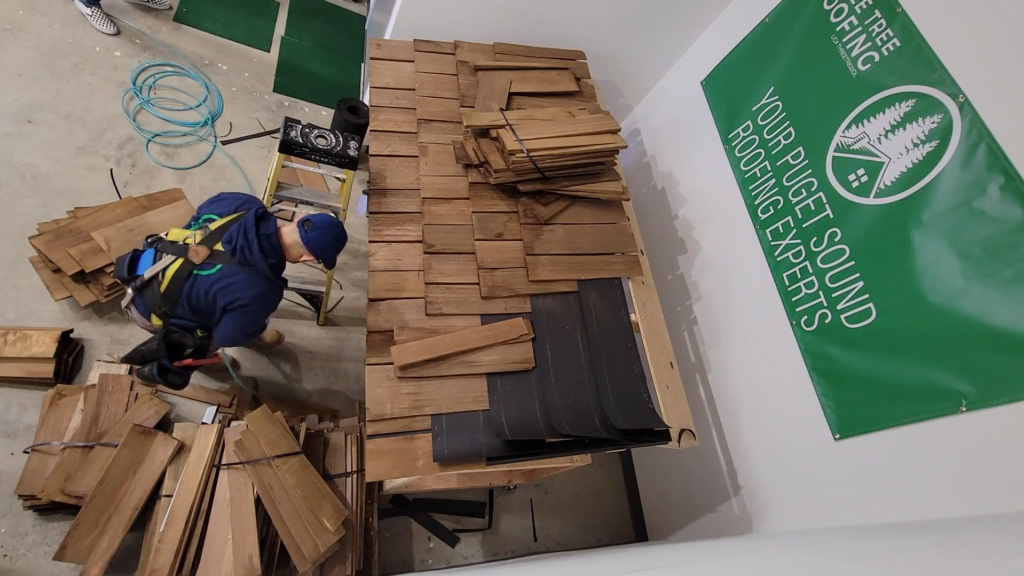 Photo of roofer installing cedar shake shingles on a demo roof for a cedar shake shingle roof.