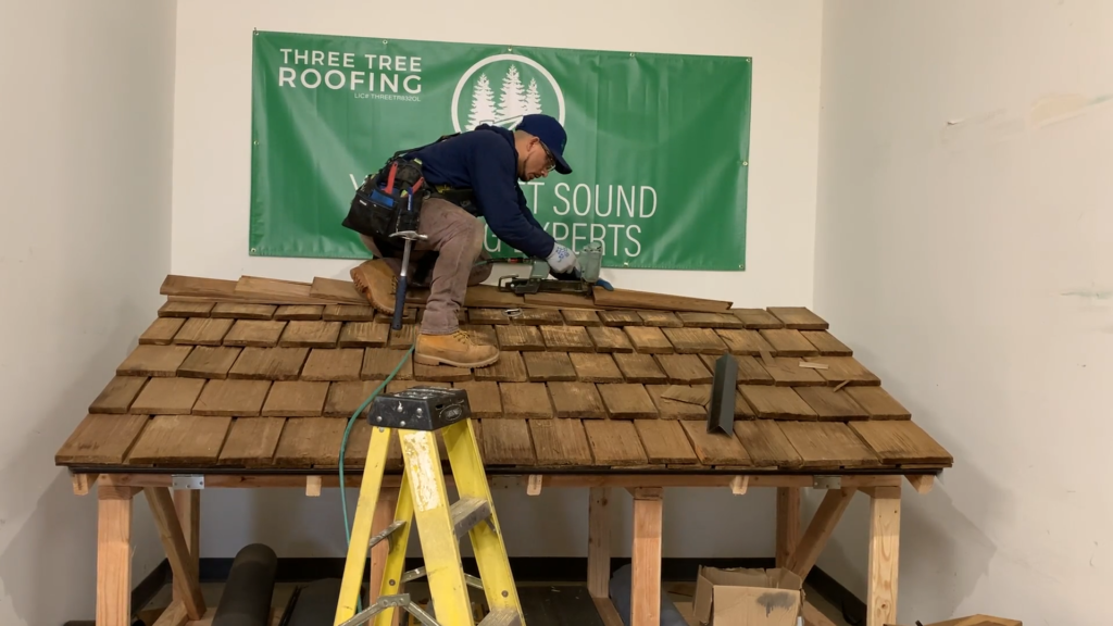 Photo of roofer installing the ridge cap on a demo roof for a cedar shake shingle roof.