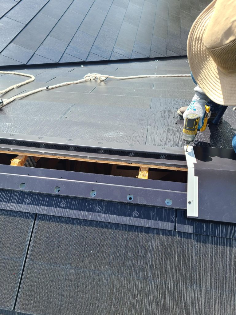 Close up view of Tesla Solar Roof tiles and ridgecap being installed